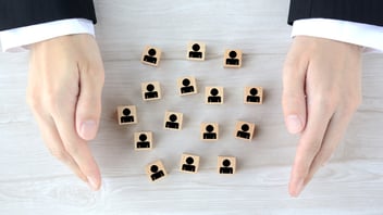 Representación de la gestión de recursos humanos y seguridad laboral, mostrando manos que protegen al personal para reducir la siniestralidad y optimizar la prima de riesgo.