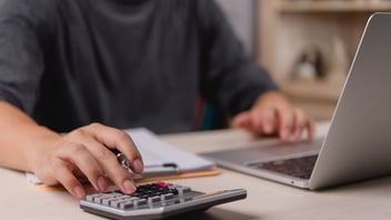 Profesional de Recursos Humanos utilizando una calculadora y laptop para gestionar el cálculo de PTU y la Declaración Anual, optimizando procesos de nómina y cumplimiento normativo en México.