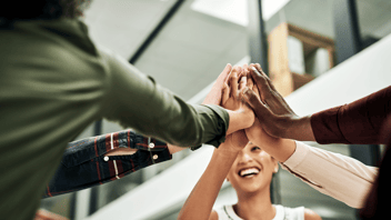 Equipo de colaboradores diverso y motivado une sus manos en el centro, como símbolo de una cultura organizacional positiva impulsada por una estrategia de bienestar integral 360.