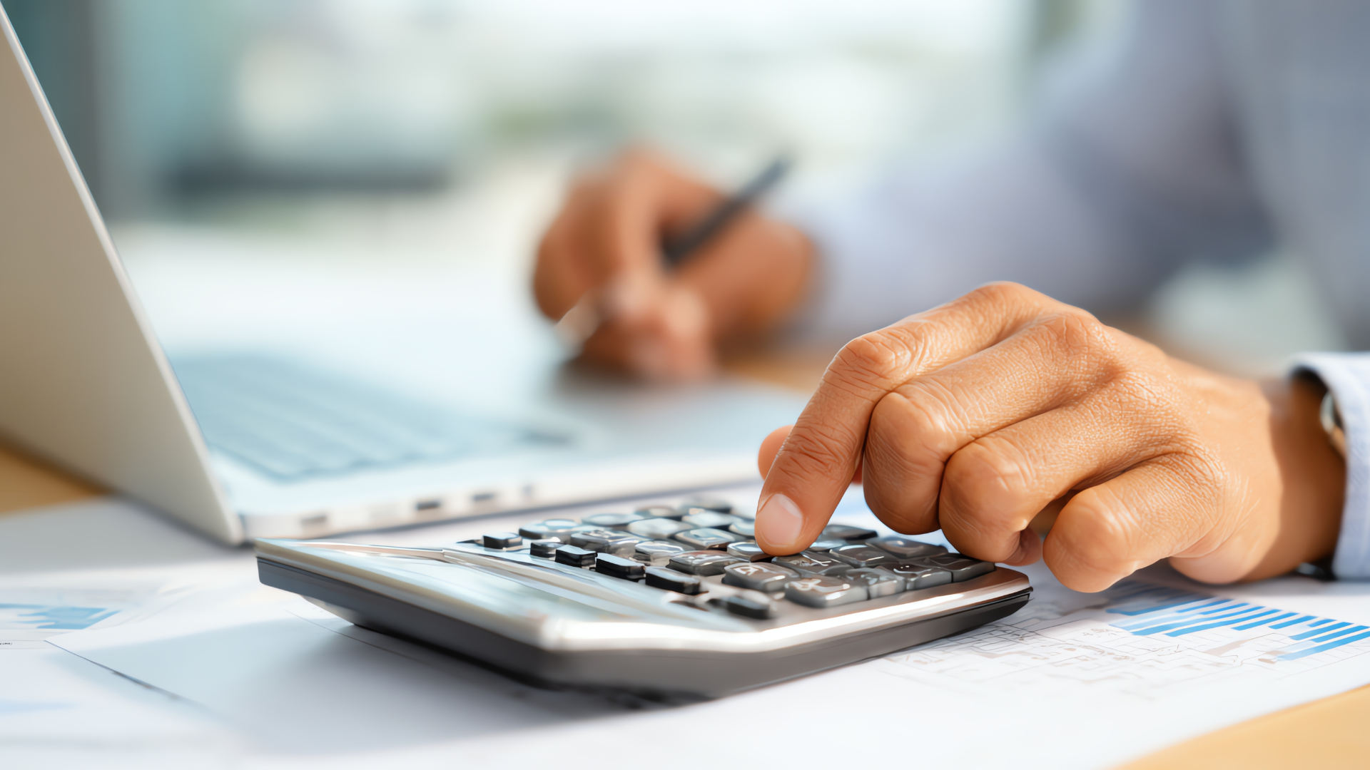 Mano de un profesional de RH usando una calculadora sobre un escritorio para realizar el cálculo de un finiquito o liquidación laboral.