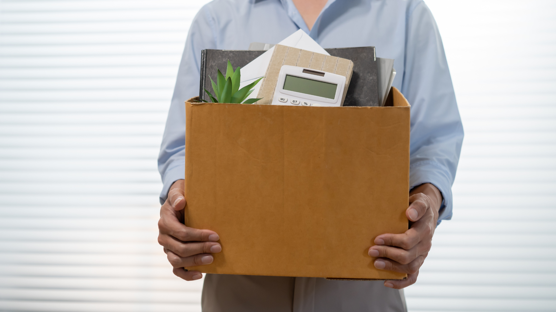 Colaborador sosteniendo una caja de pertenencias de oficina con una calculadora, representando la renuncia voluntaria y el cálculo de finiquito en México.