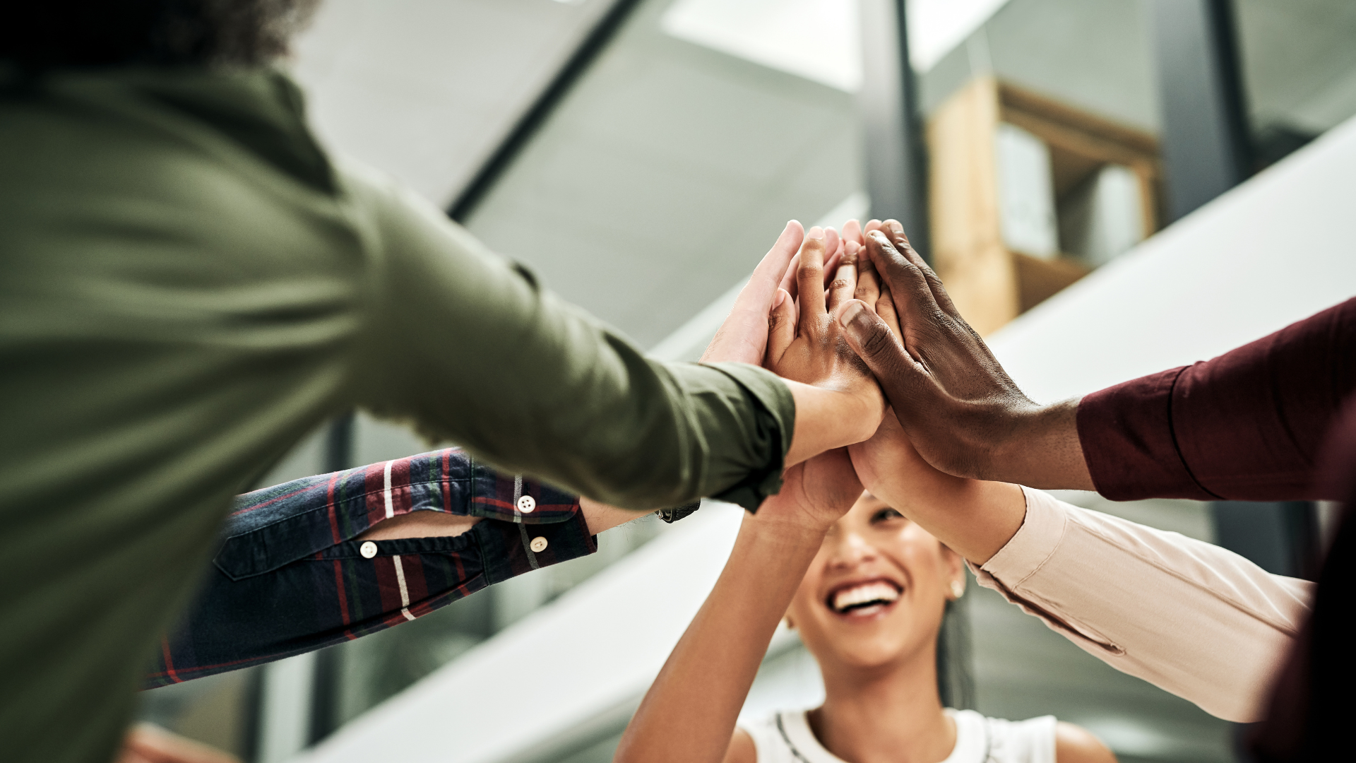 Equipo de colaboradores diverso y motivado une sus manos en el centro, como símbolo de una cultura organizacional positiva impulsada por una estrategia de bienestar integral 360.