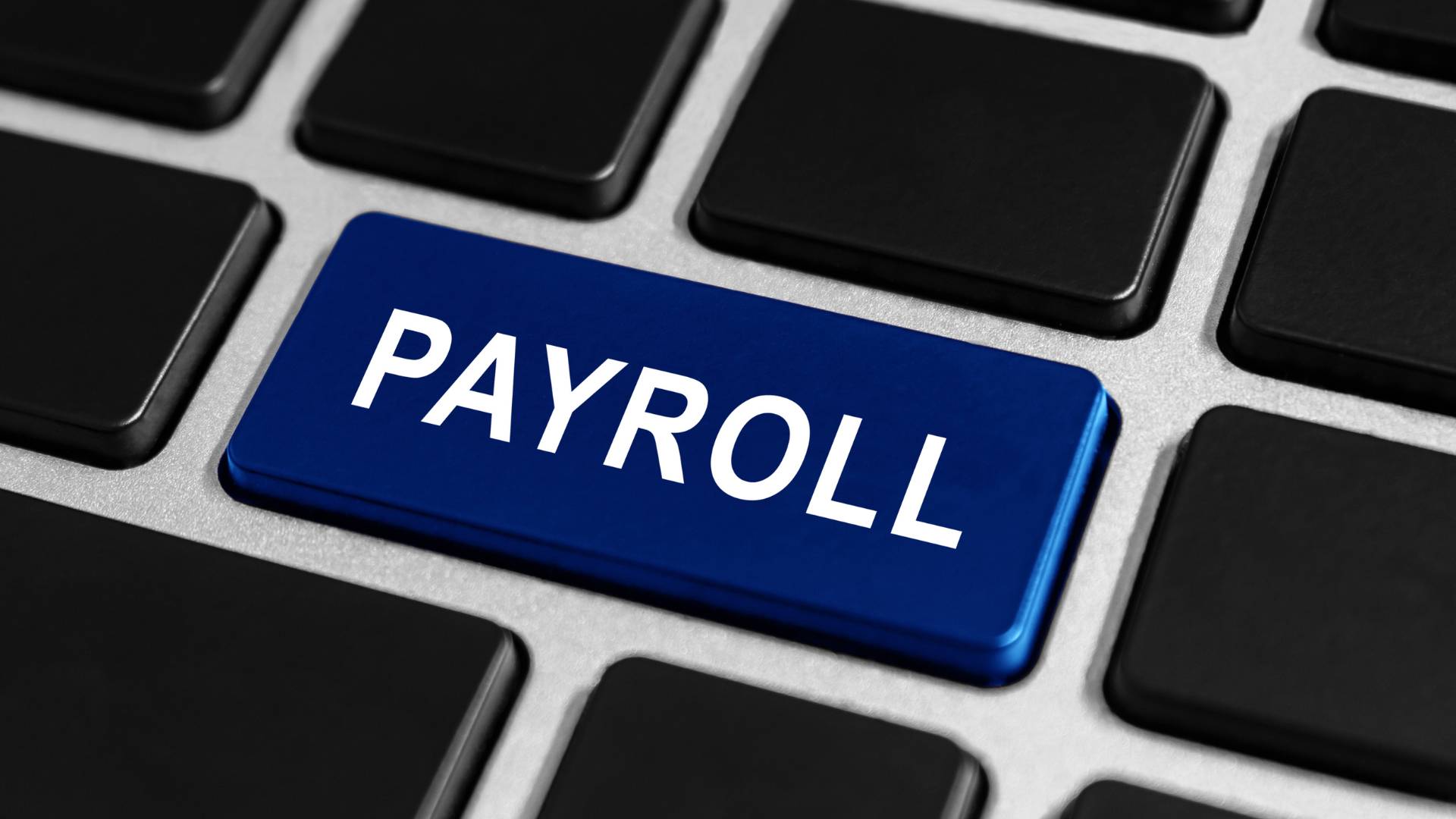 Primer plano de un teclado de computadora con una tecla azul que dice PAYROLL, simbolizando la simplificación del procesamiento de nómina a través de un servicio de Recursos Humanos especializados.